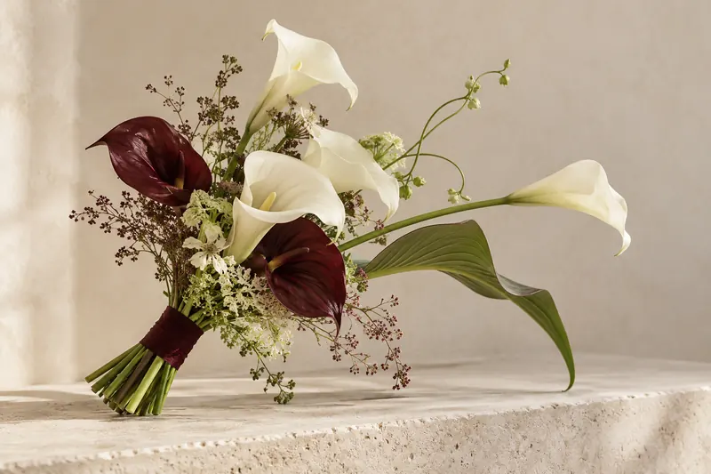 Original sculptural bouquet concept with ivory trumpet-shaped blooms, burgundy accents and curved green stems.